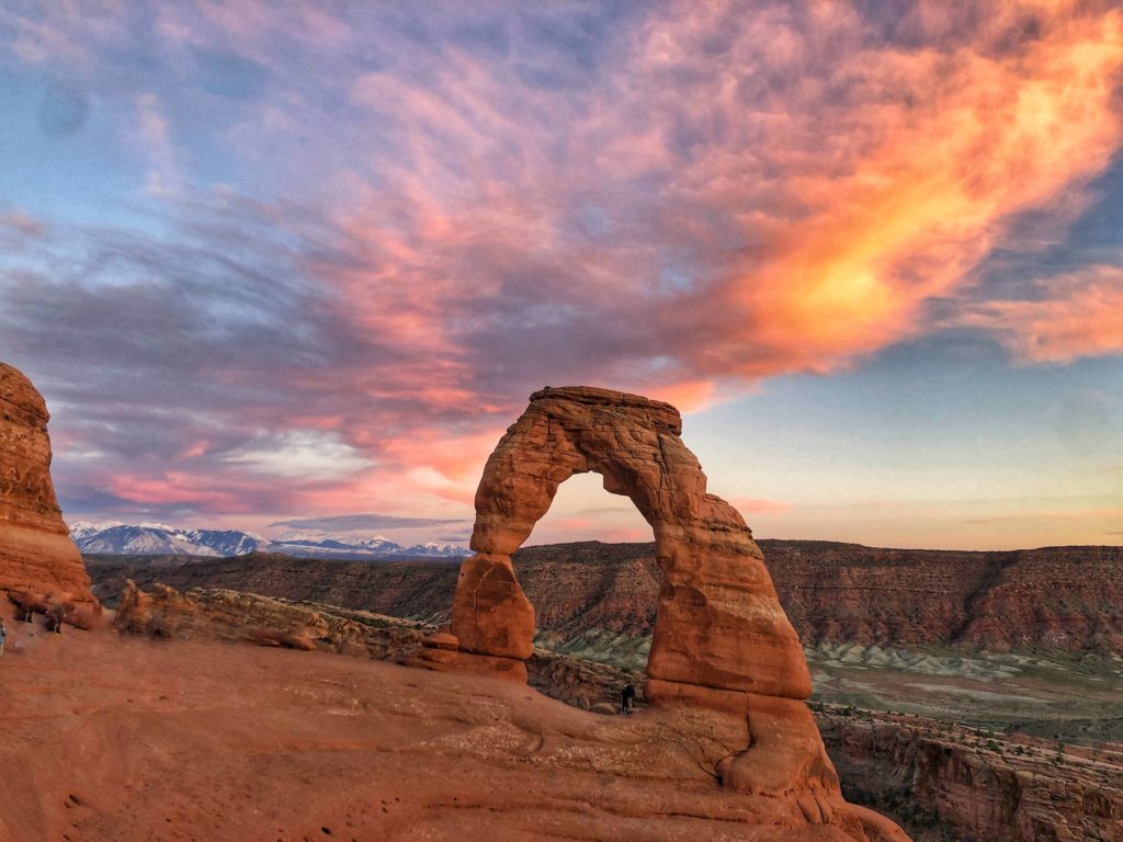 Delicate Arch at sunset with pink clouds behind