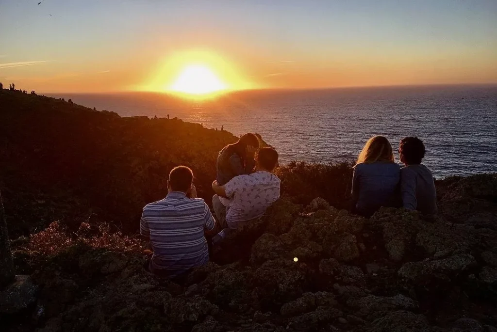 Sagres end of the world with people sitting on it at sunset