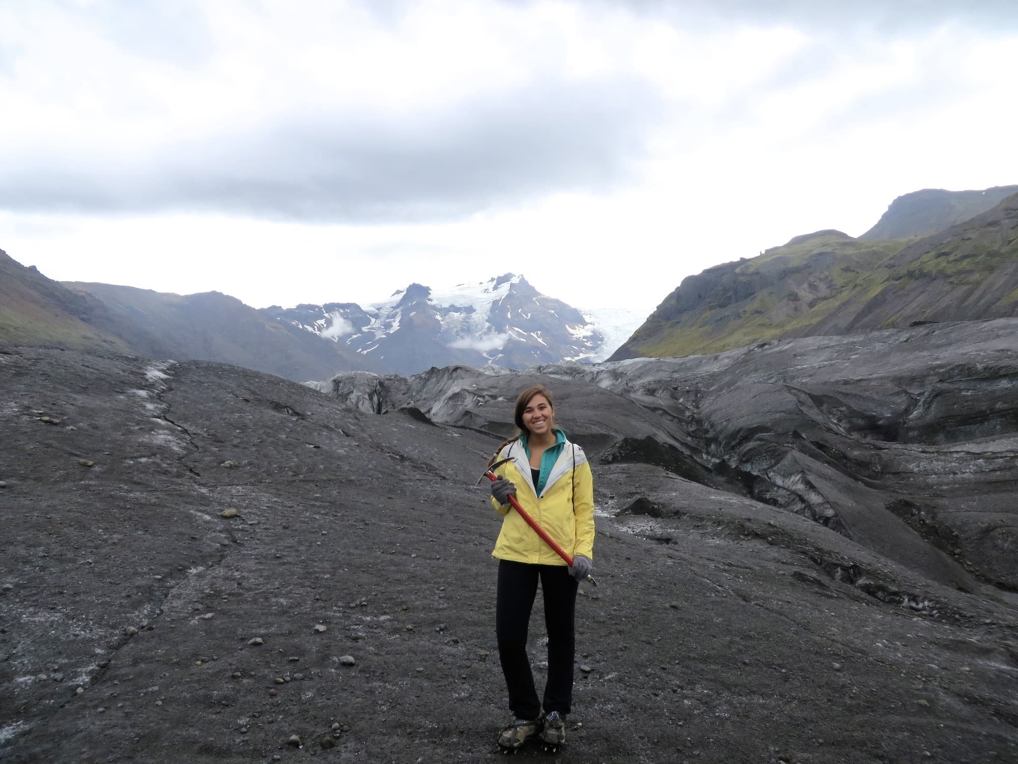 Girl standing in front of Glacier with axe in hand