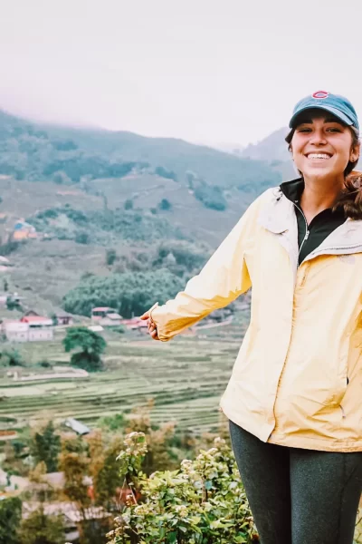 girl standing and smiling with rice paddies of sapa behind her