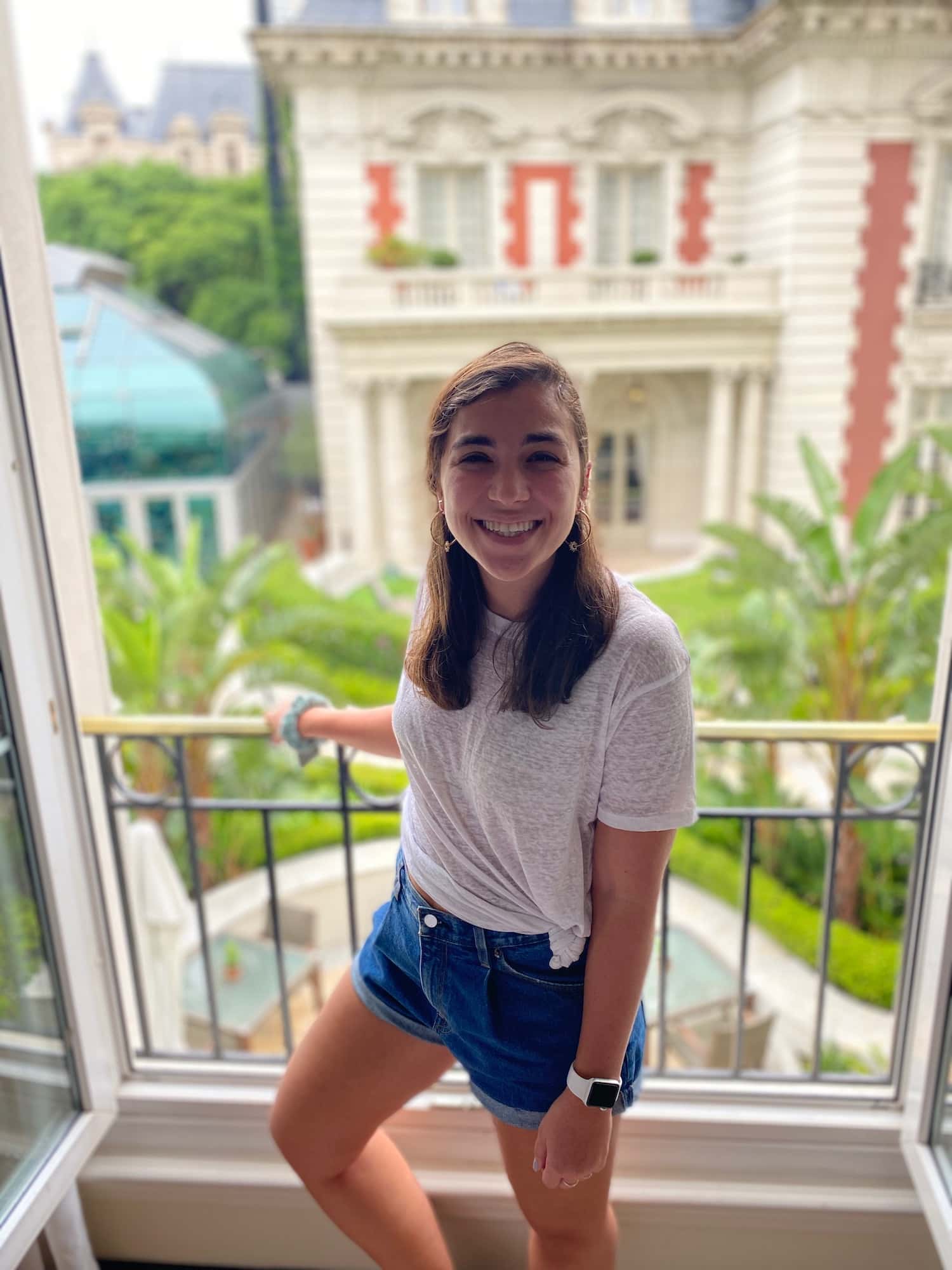 Female standing on balcony in front of building