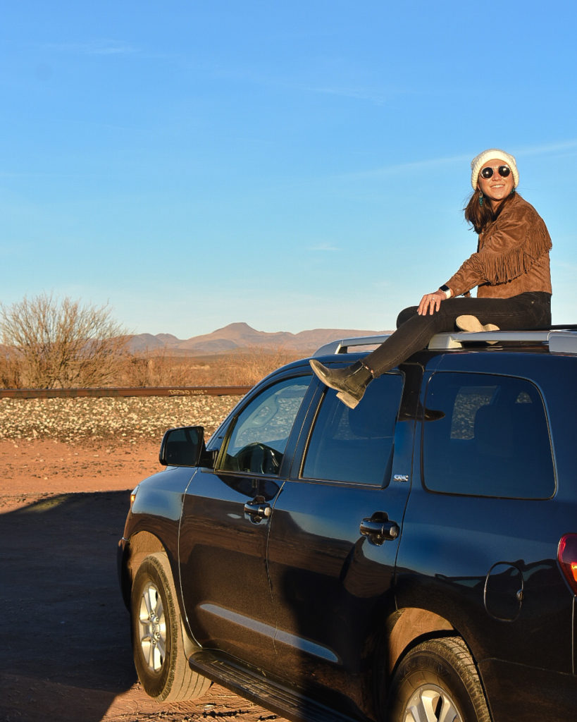 Girl sitting on top of car, Best Road Trip Games cover