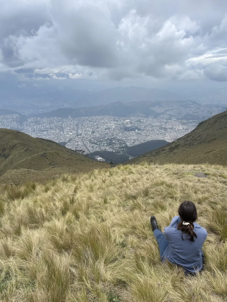 girl sitting on top of mountain looking over quito