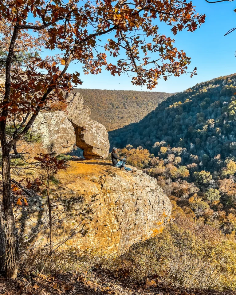 Woman sitting on the edge of whitaker point in the fall with fall colors