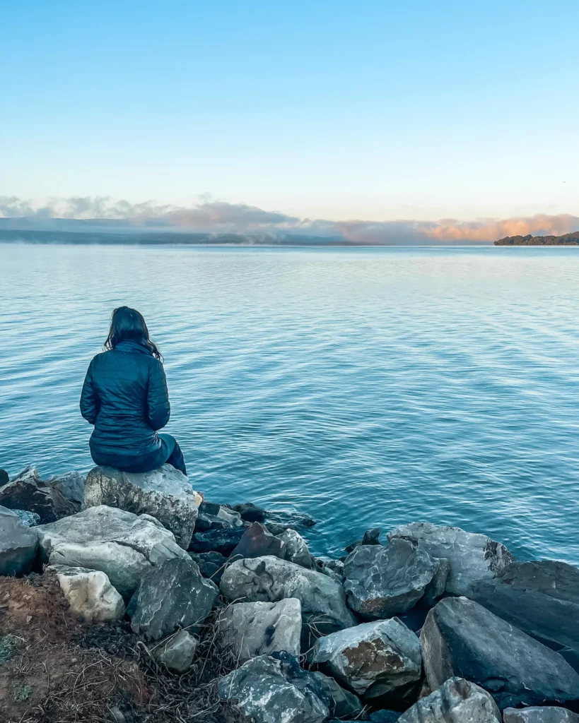 Woman sitting on rock by lake