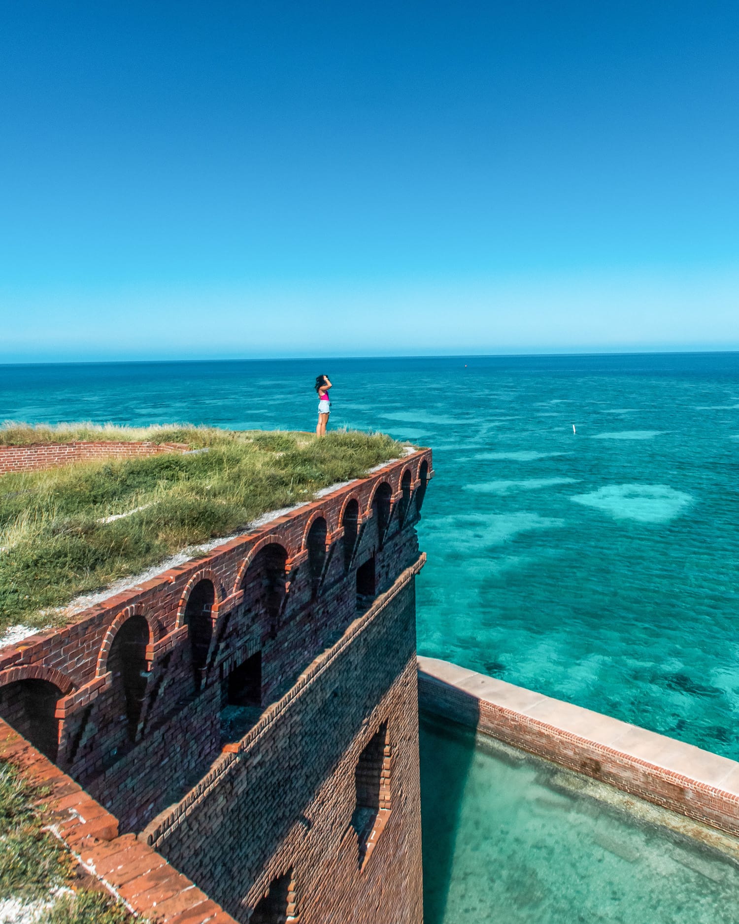 I am standing on top of Fort Jefferson overlooking crystal clear blue waters beyond