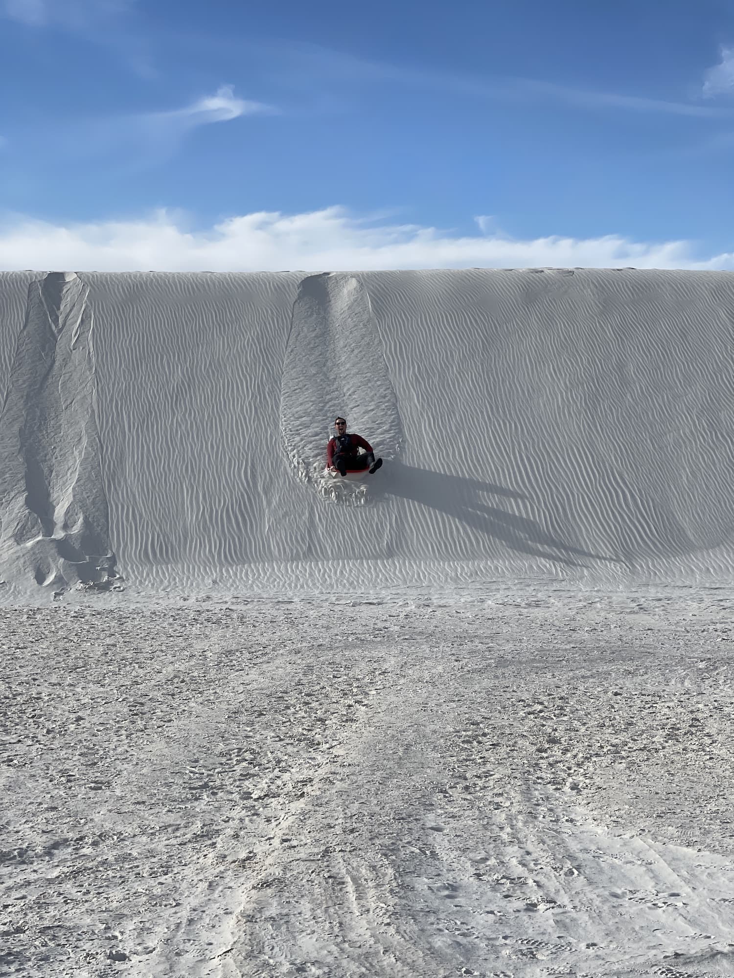 Dylan sledding down the dune with smile on his face