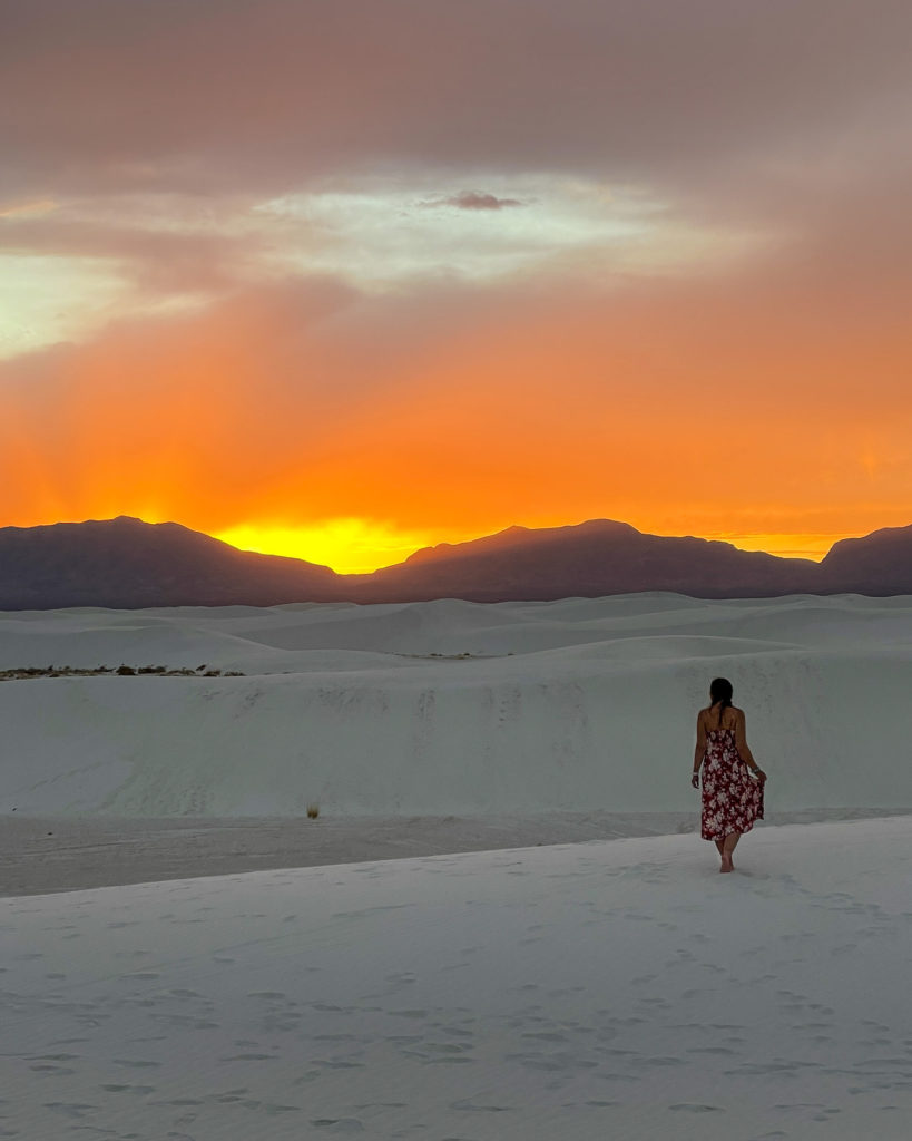 Me walking in dunes with sunsetting behind the mountains, bright orange colors
