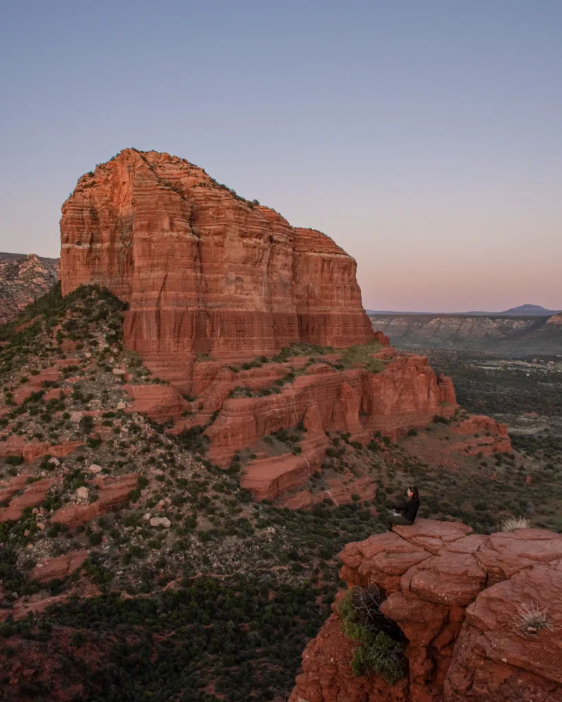 View of large rock formation with girl sitting on a ledge