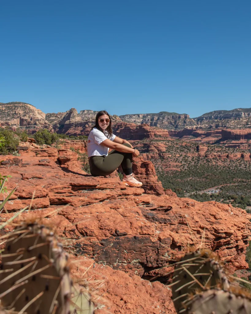 Views of Red Rocks with girl sitting on the top of a ledge on doe mountain