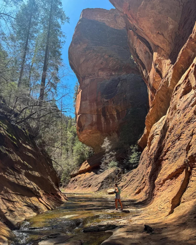 tall cliffs on either side of girl walking in river