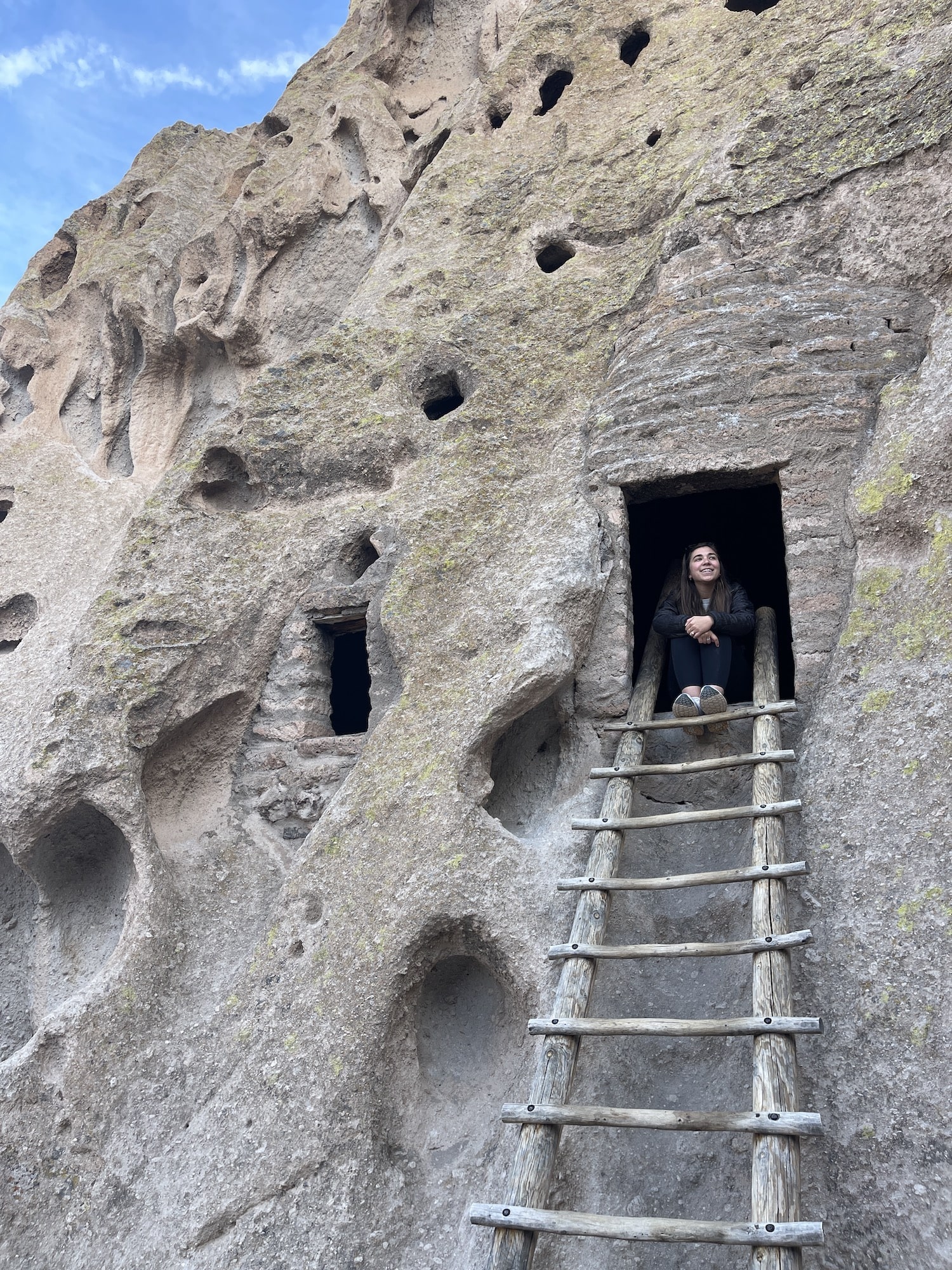 Girl sitting in cliff dwellling at bandalier national monument