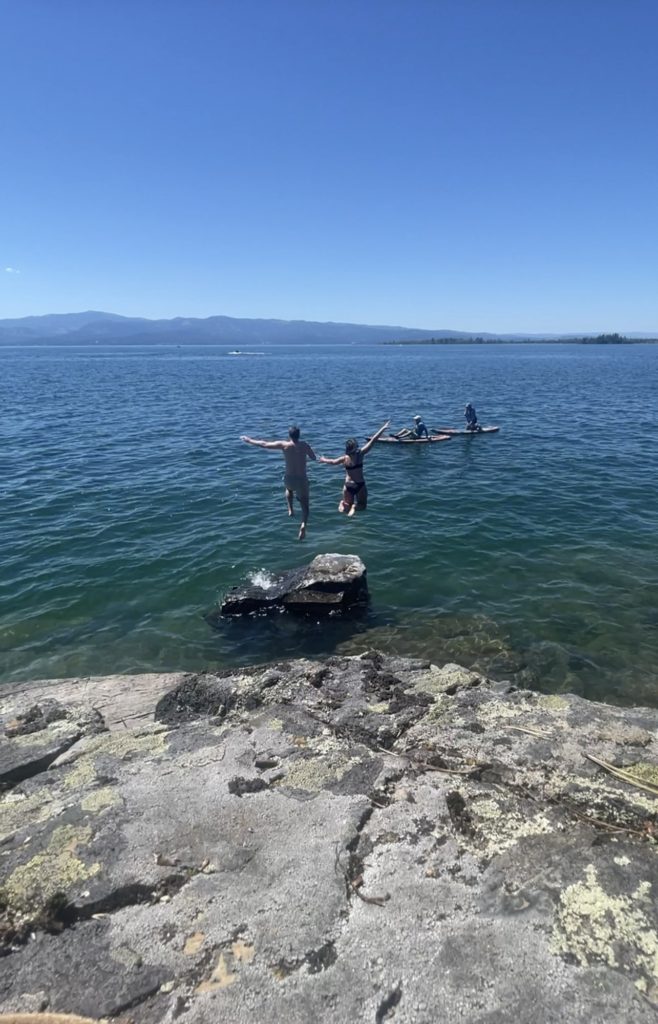 two people jumping off rock at flathead lake