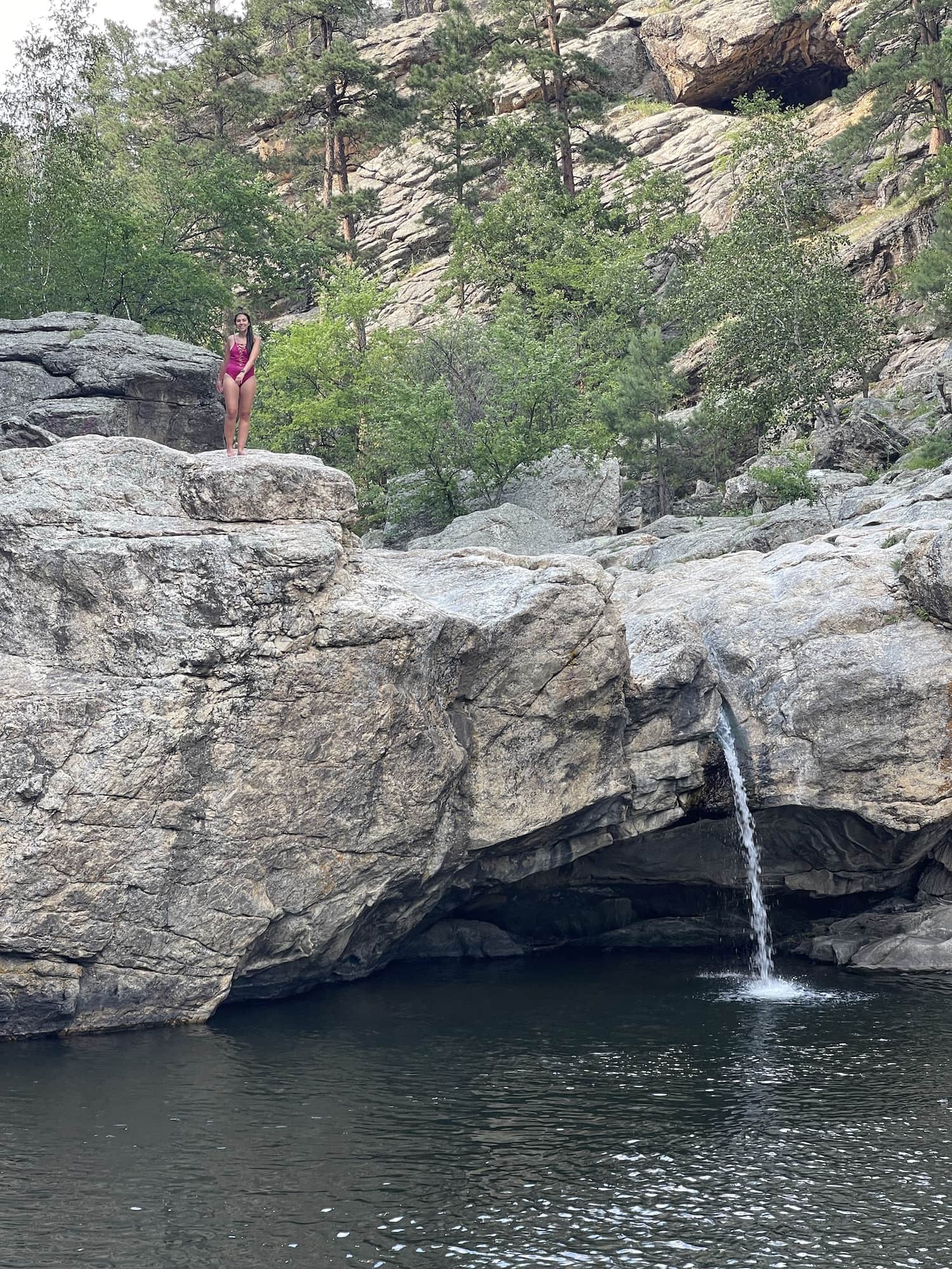 girl standing on cliff above hippie hole