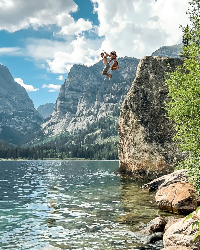 two people jumping off rock into phelps lake