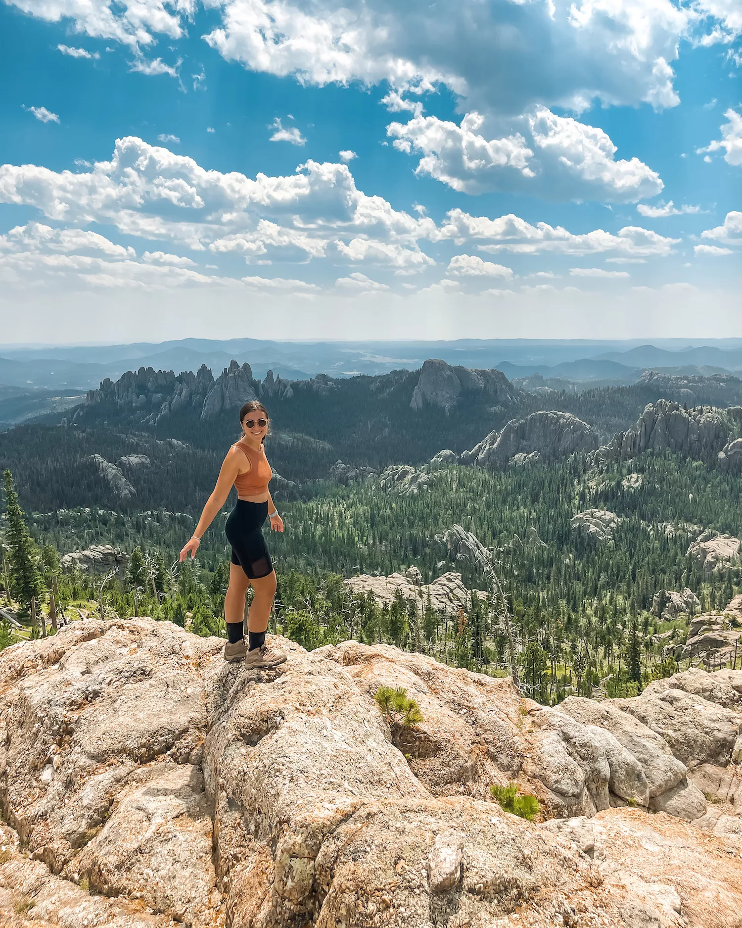 girl on top of black elk peak in south dakota with black hills rising up behind