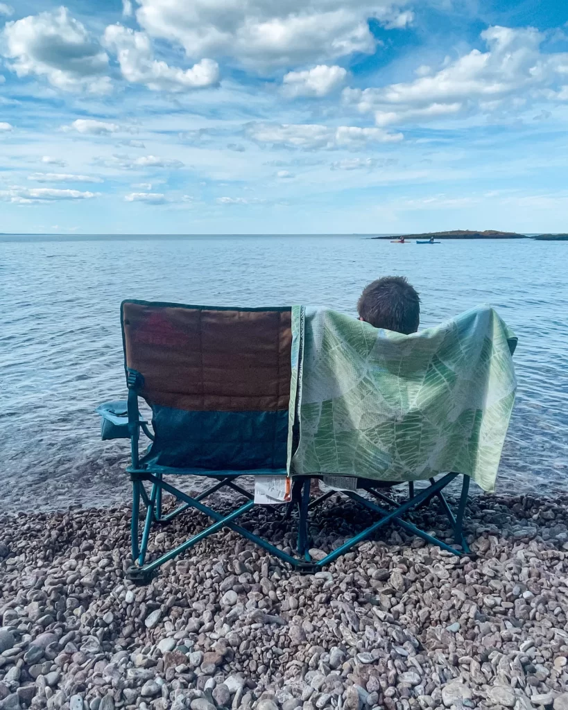boy sitting in a lounge chair with lake superior in front of him