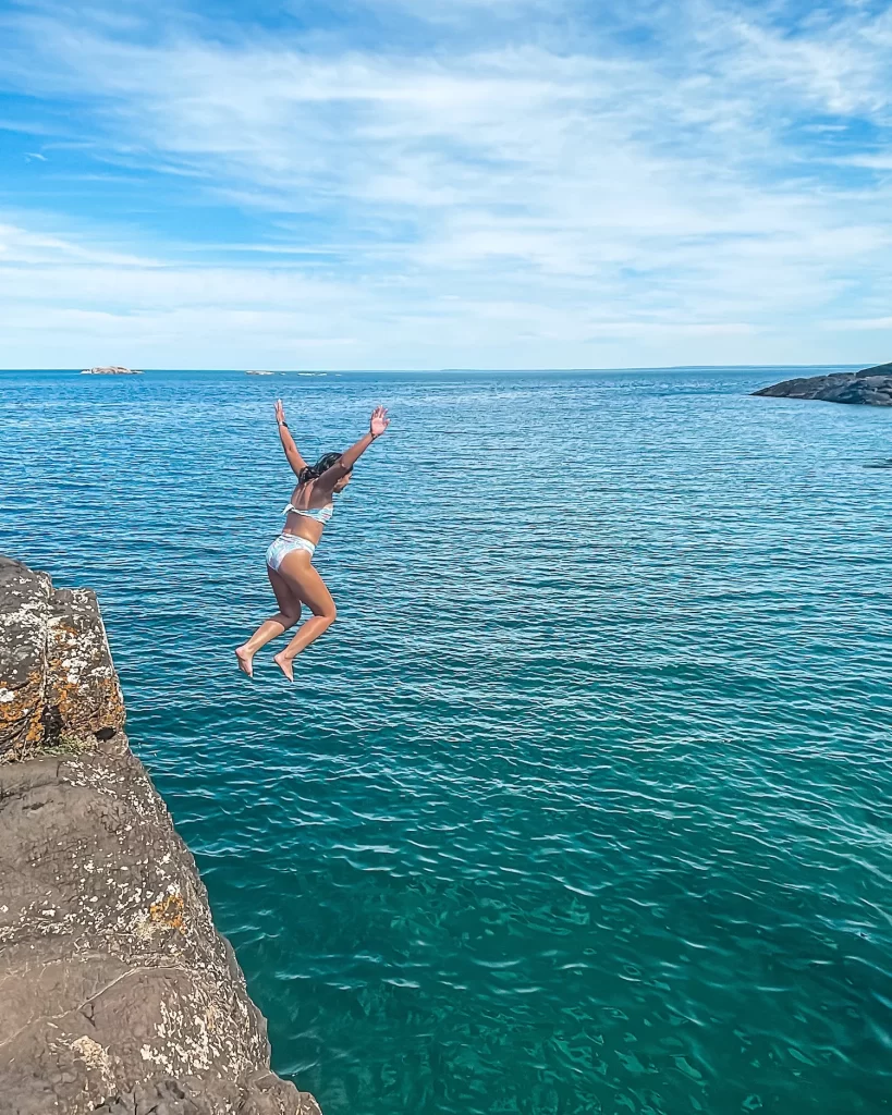 girl jumping mid-air off a cliff in preque isle state park