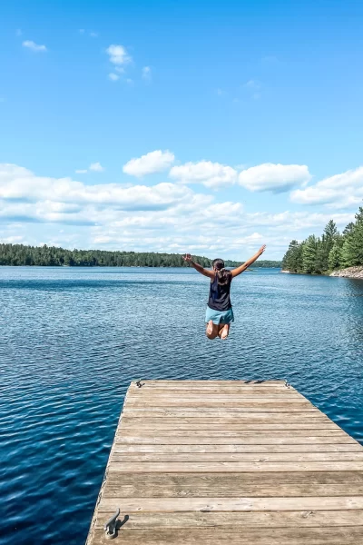 girl jumping on a dock with Lake Superior in front of her, waters of Voyageurs National Park