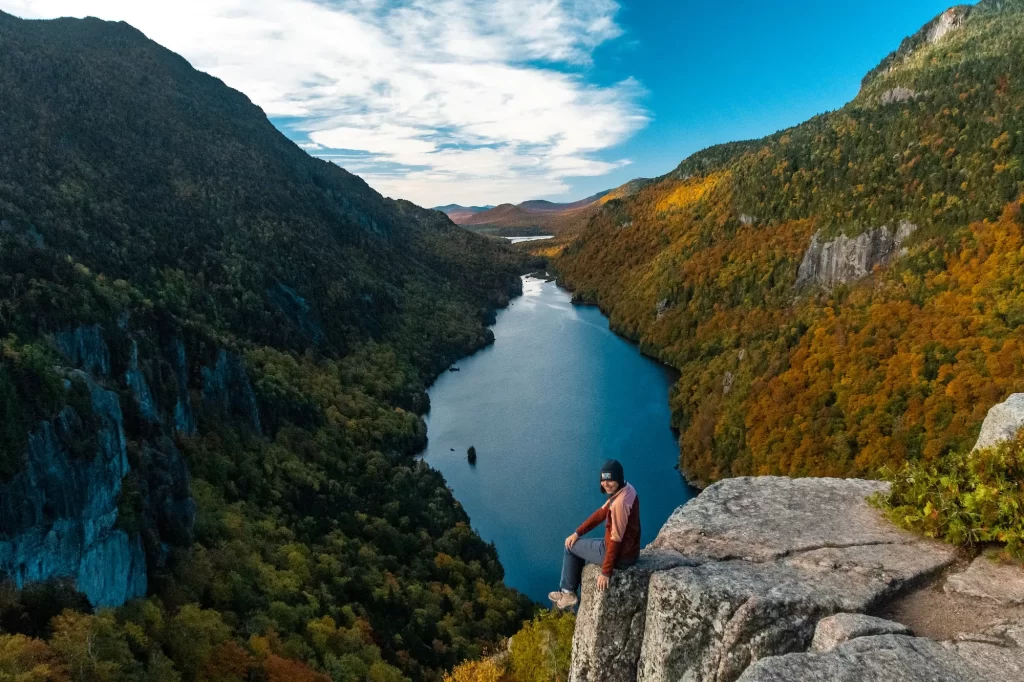 girl sitting on the edge of the mountain with view over lake ausable behind