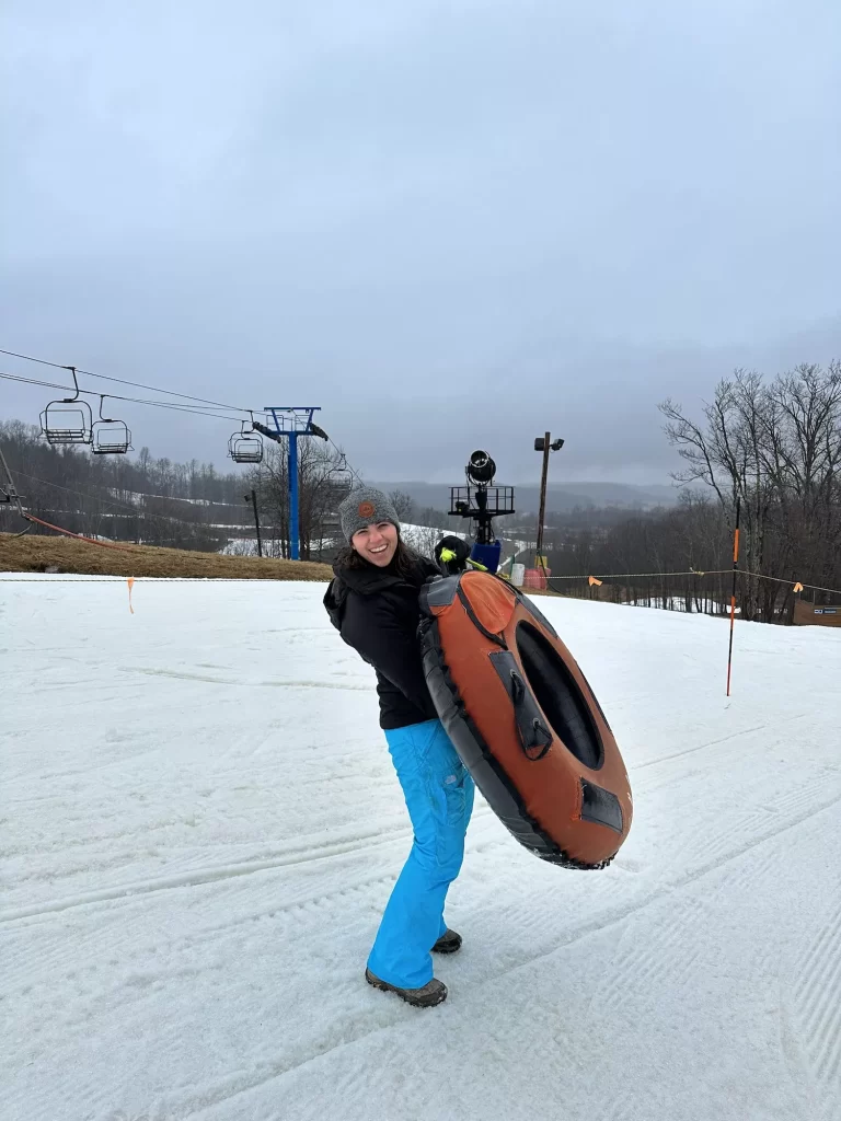 girl carrying a snow tube and laughing at winterplace ski resort