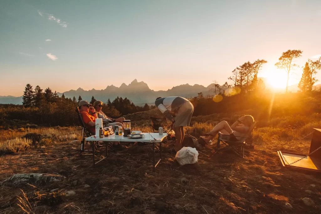 people sitting around a table with sunset at free campsite bridger forest