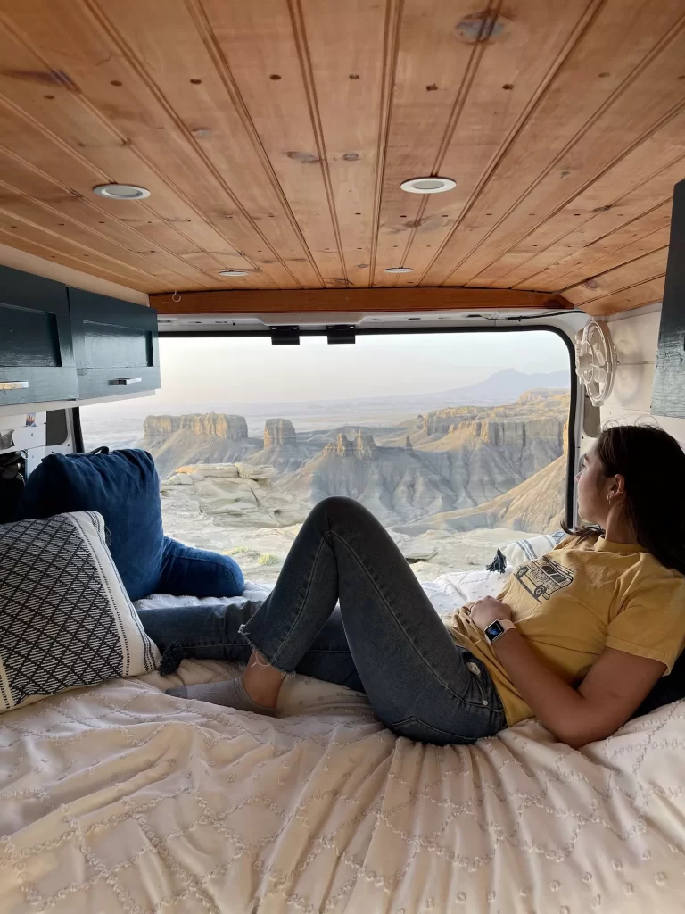 girl sitting in her van looking out over moonscape overlook