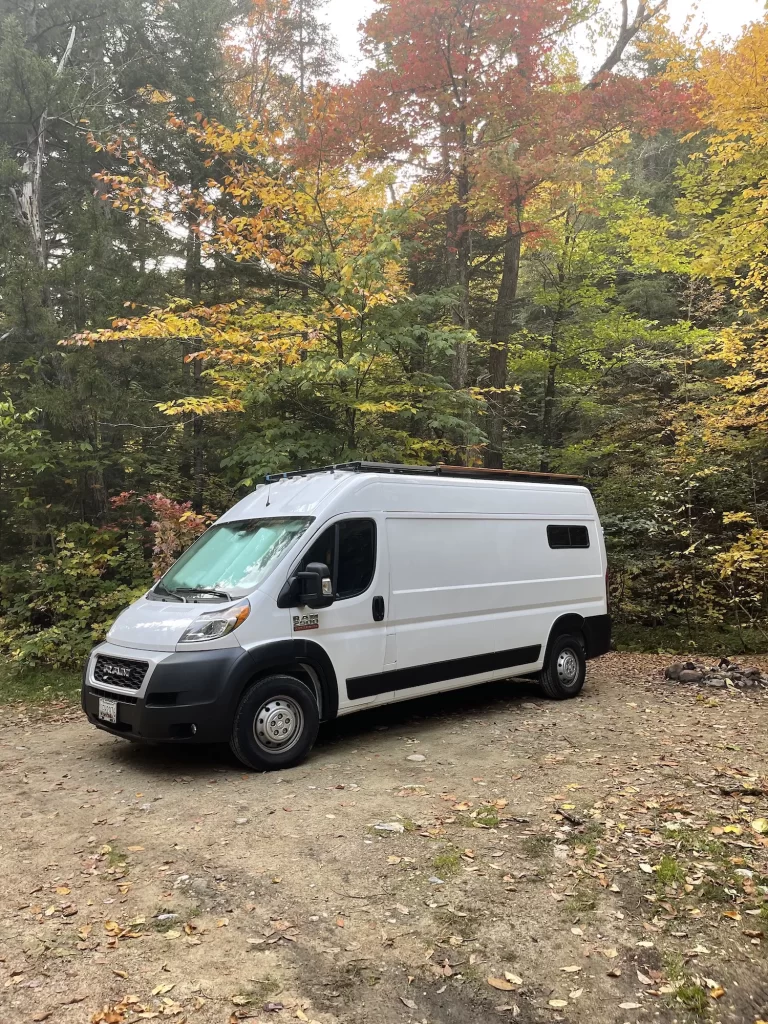 van in the middle of White Mountains National Forest with yellow and green trees behind