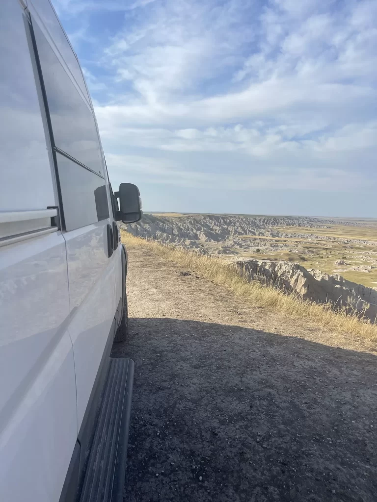 Side of a van in front of badlands at a camping site