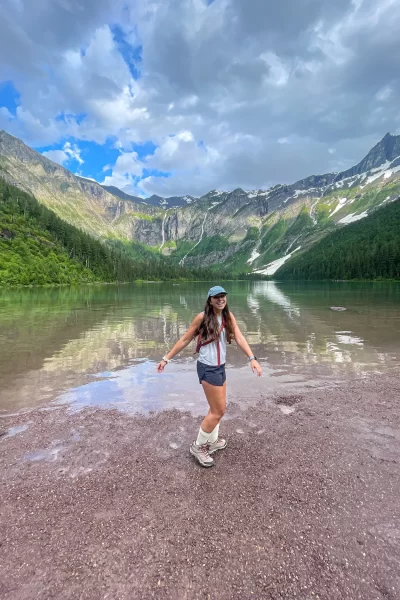 girl standing and laughing in front of Avalanche lake in glacier national park