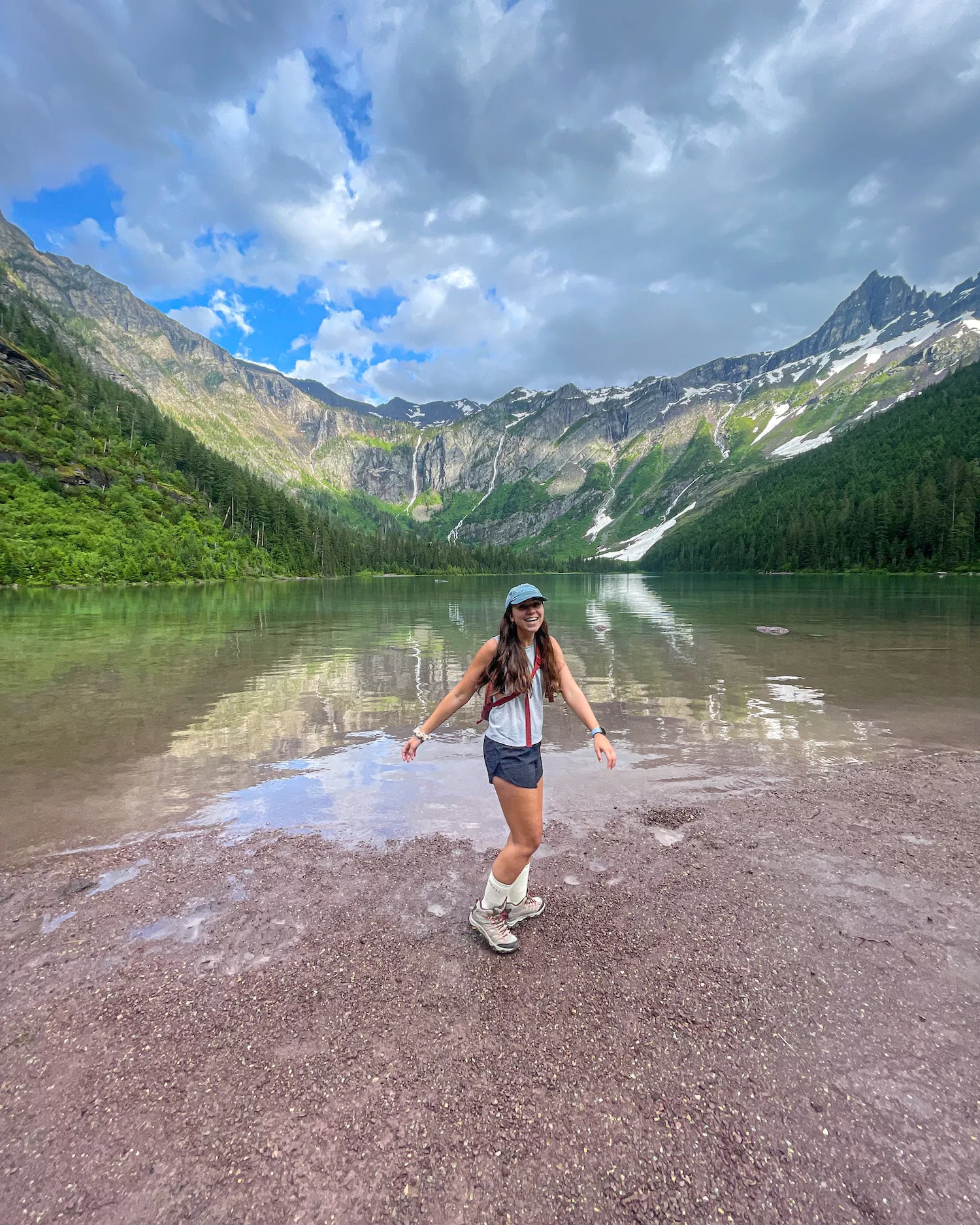 girl standing and laughing in front of Avalanche lake in glacier national park