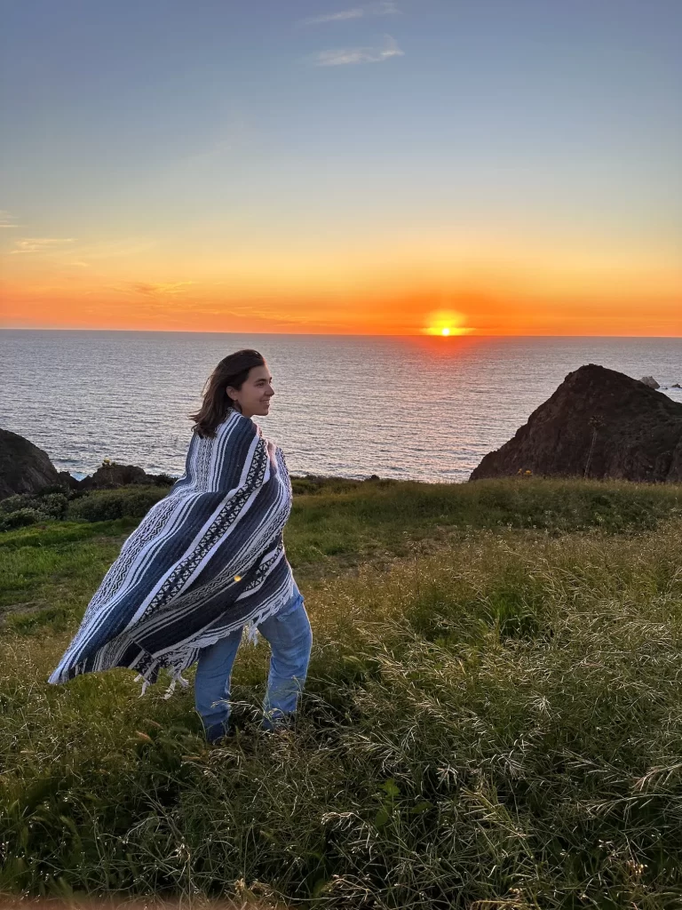 Girl standing in front of coastal sunset