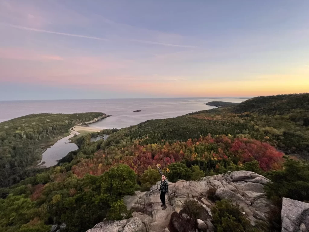 girl standing on the summit of Beehive with the water behind