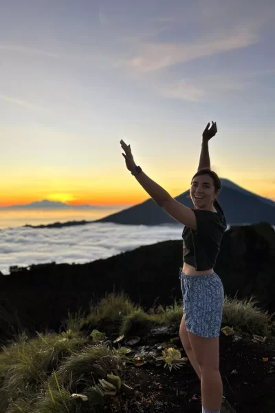 girl with hands up in front of the sunrise at Mount Batur