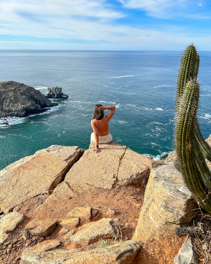 girl sitting on the peak of the punta lobos hikes