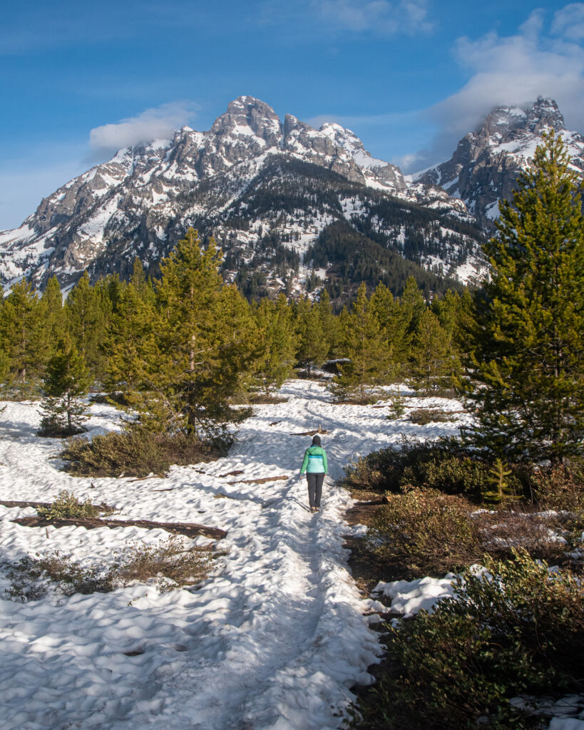 girl walking snow covered trail with tetons behind her