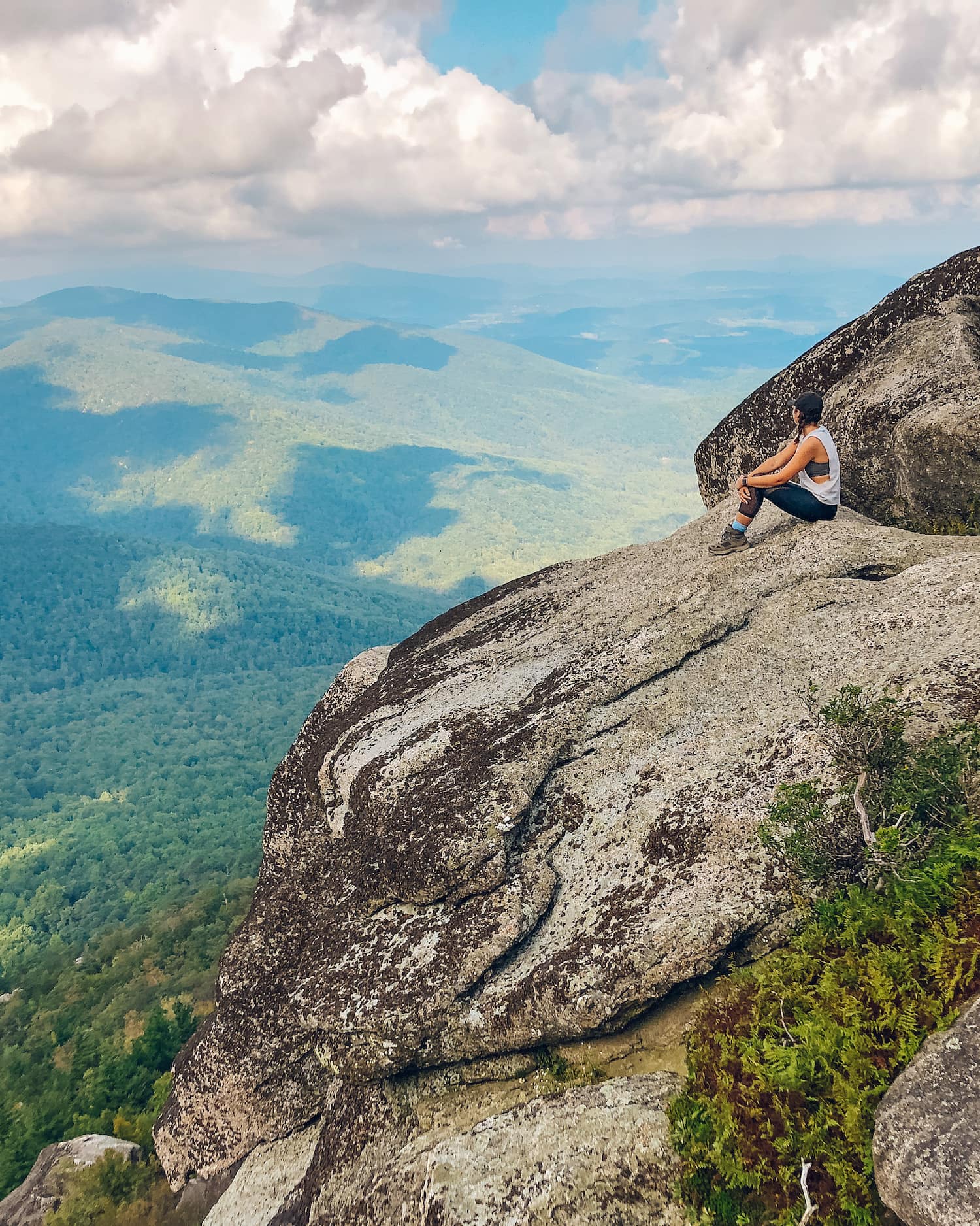 girl sitting on the top of old rag mountain summit with green trees behind