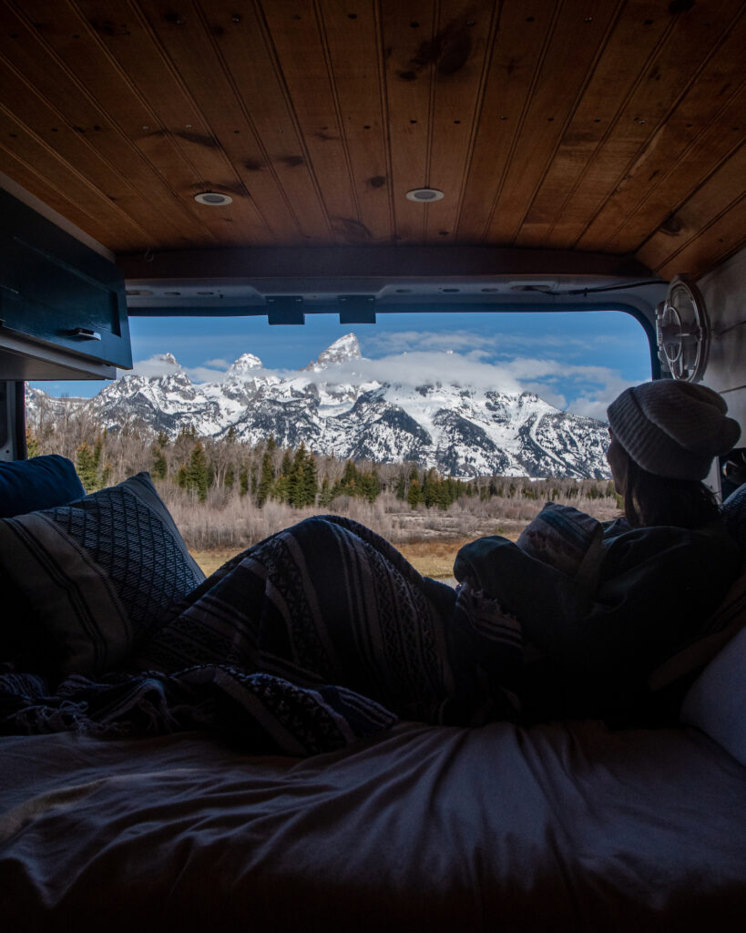 girl in her van with the tetons behind 