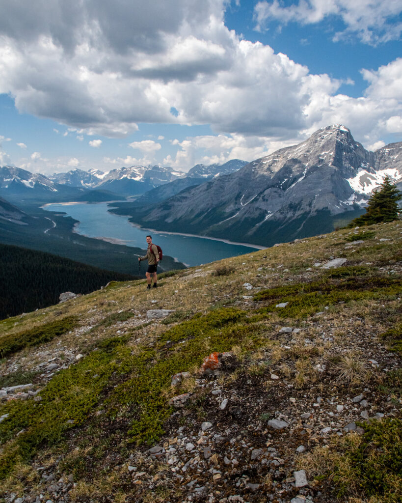 boy on a hillside overlooking spray lakes and rocky mountains over the lake