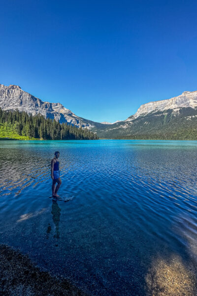 girl standing on a rock in Emerald Lake Yoho National Park with bright blue water