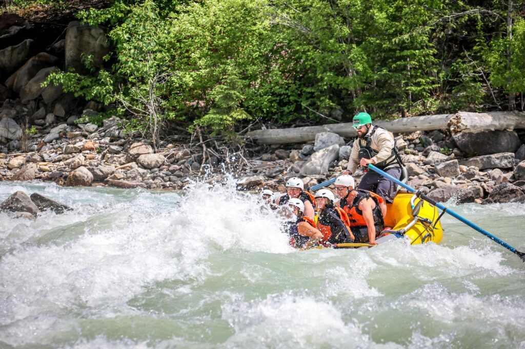 A raft getting half covered by a rapid in the Kicking Horse River