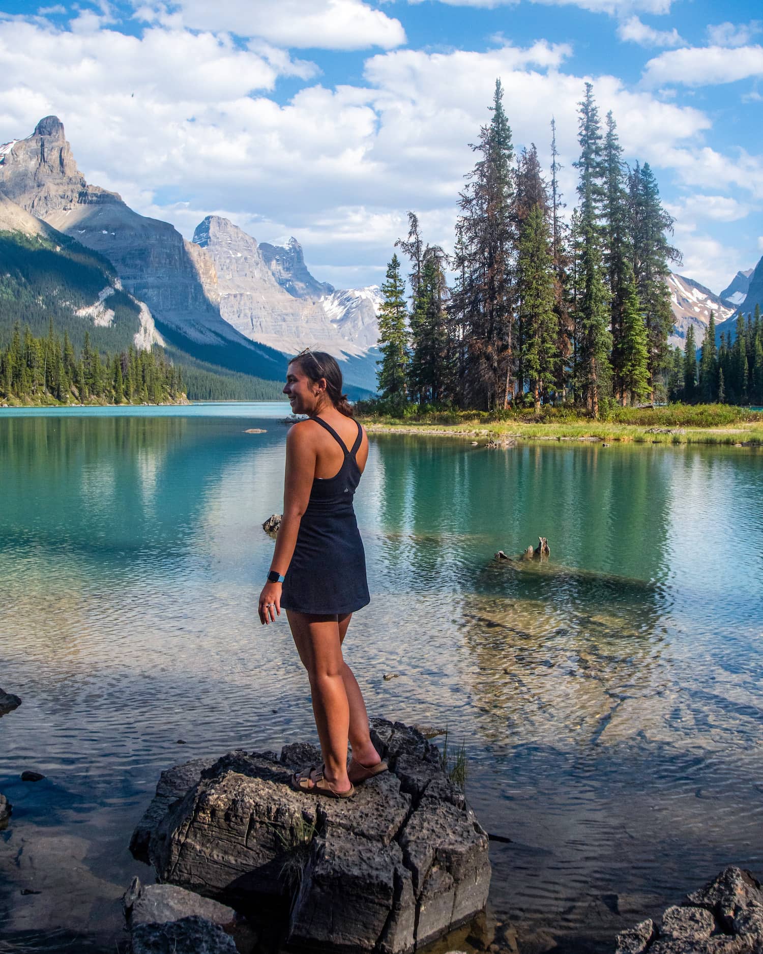 girl looking out at landscape of Spirit Island in Jasper National Park, mountains and island behind her with blue lake