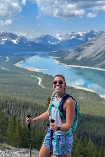 girl smiling on the top of a mountain in Kananaskis with spray lakes and mountains behind