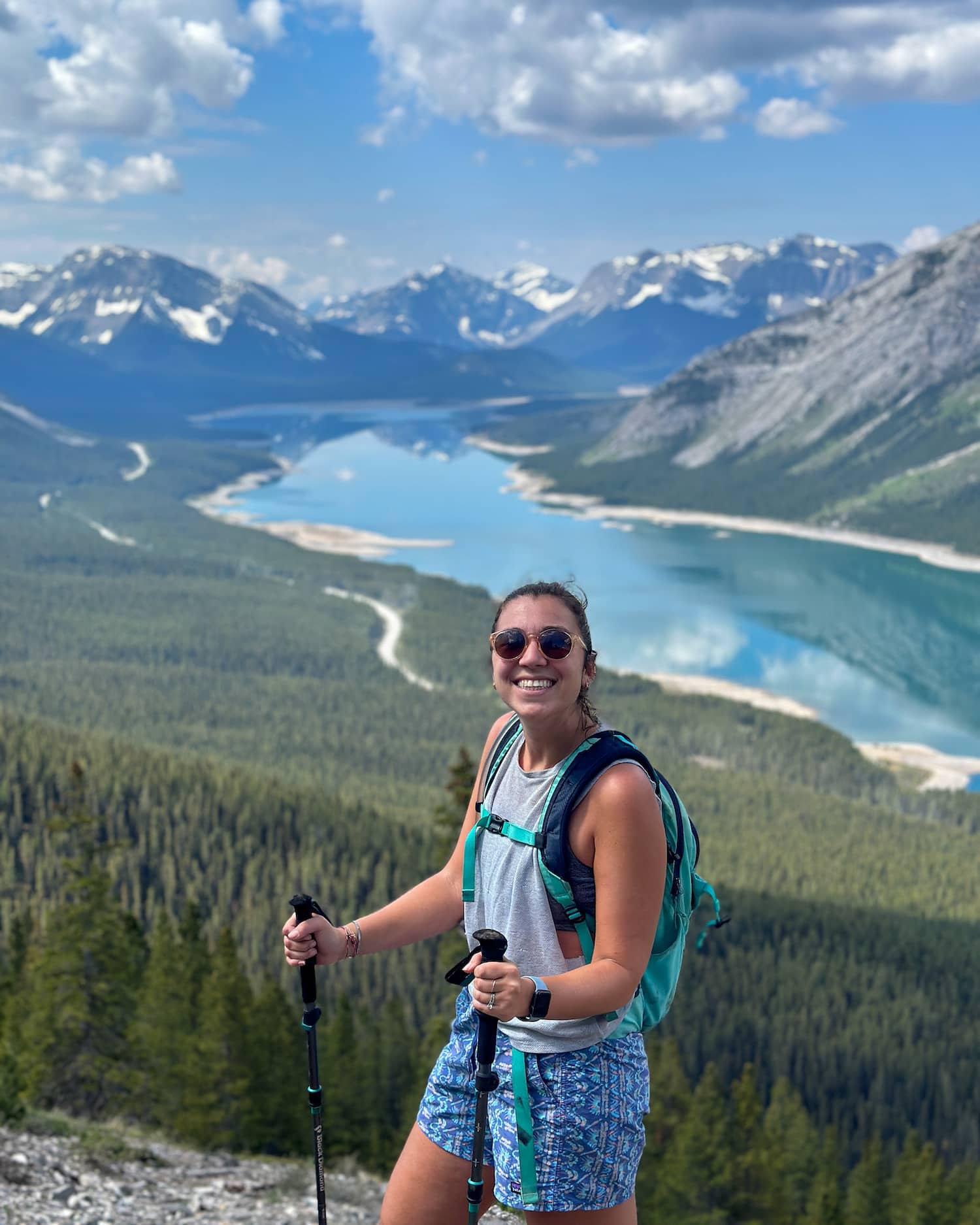 girl smiling on the top of a mountain in Kananaskis with spray lakes and mountains behind
