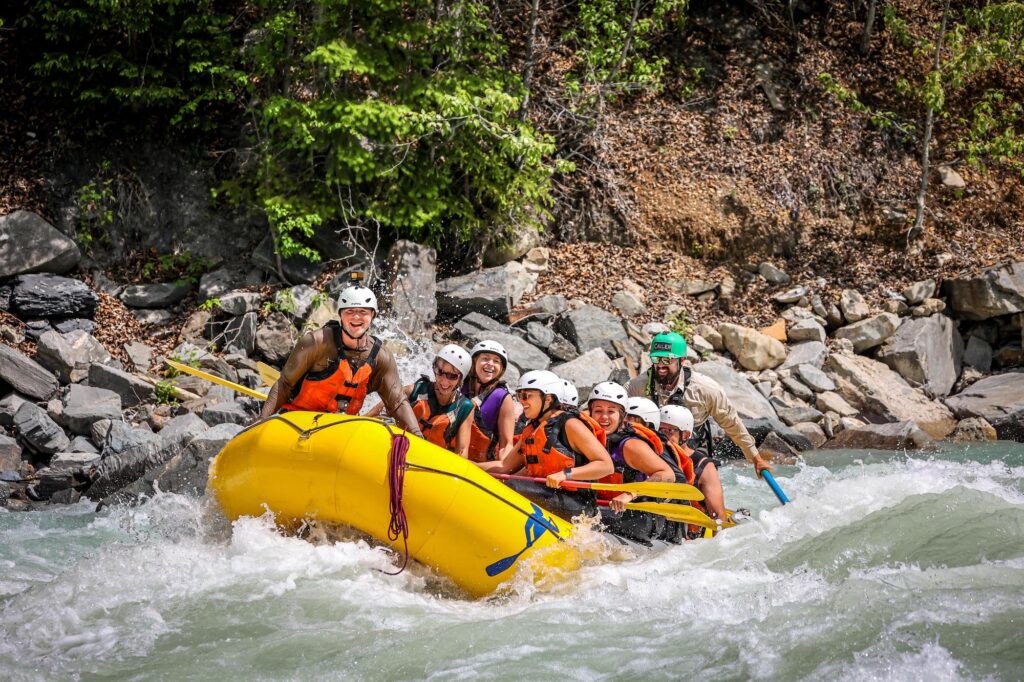 people in a raft sitting up and smiling out as they go through the Kicking Horse River