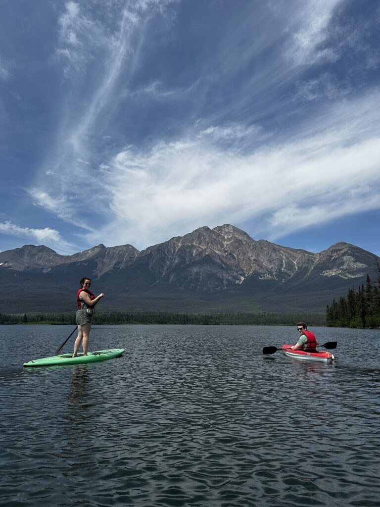 Two people paddling on a lake with mountain behind them