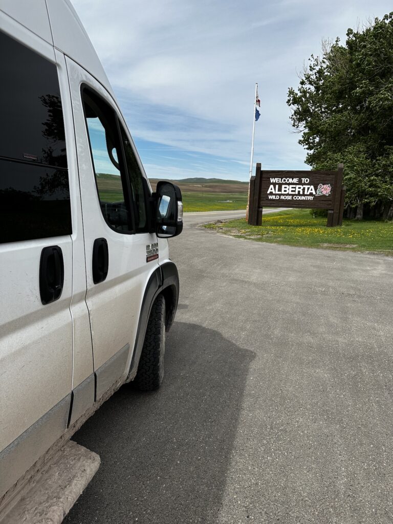 van in front of a welcome to alberta sign