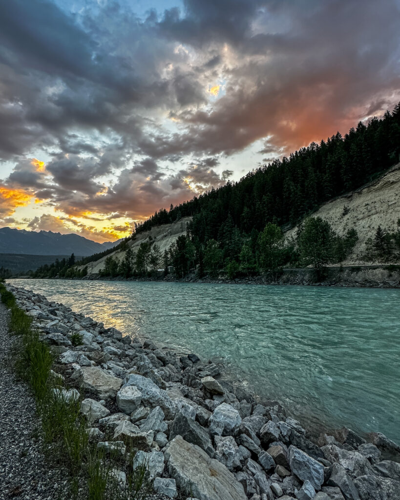 sunset behind the Kicking Horse river with mountains on the shores