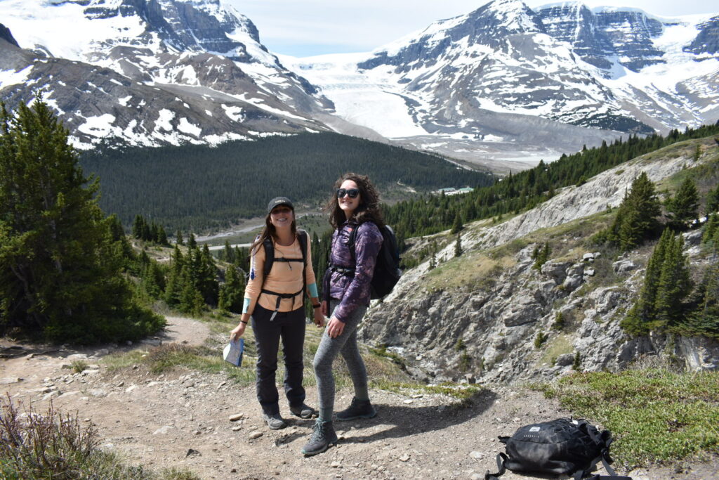 Two Girls looking back as views of glacier and mountains behind them
