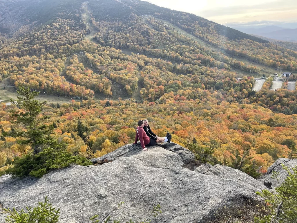 two people sitting and looking out on fall colored mountains in white mountains